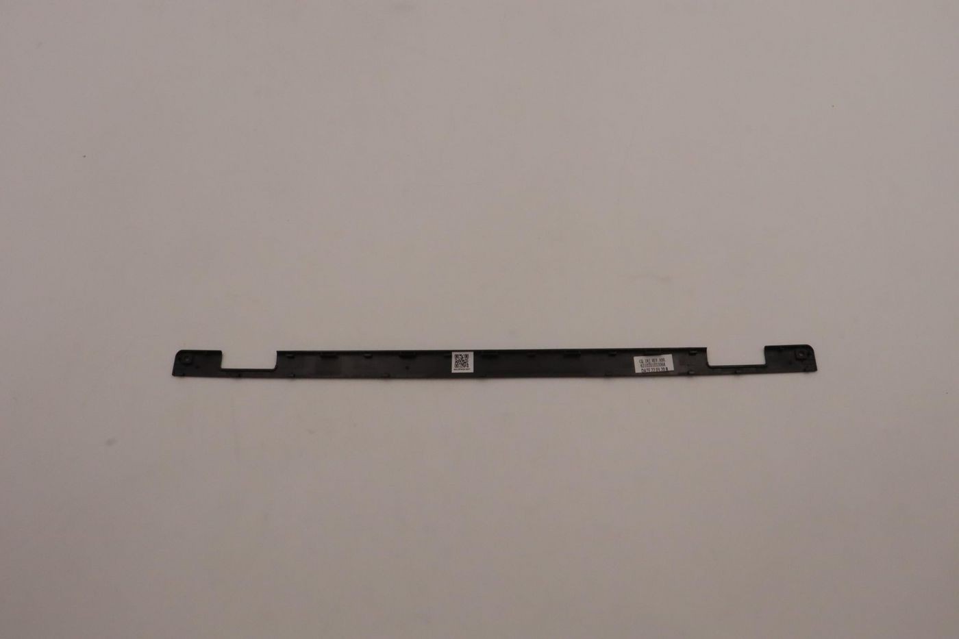 Black Lenovo COVER STRIP YG BK L13 Fenrir, a slim plastic strip with mounting holes and labels, designed for securing components in Lenovo devices.