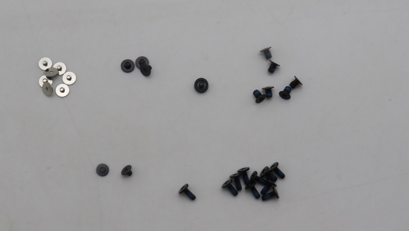 Assorted mechanical screws in various sizes and colors, including shiny silver and black, arranged on a light surface.