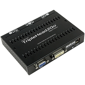 Matrox TripleHead2Go Digital Edition is a compact black device with ventilation slots, featuring multiple video output ports including DVI and VGA for connecting three monitors.