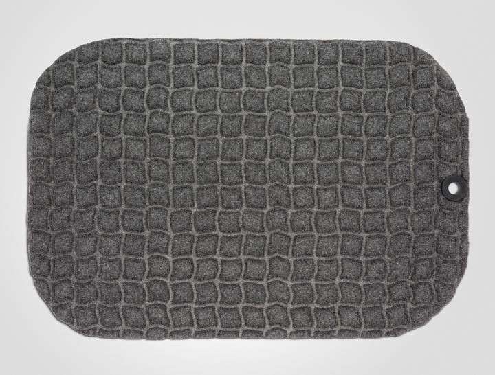 Grey mat with a textured, raised pattern resembling small squares, featuring a rounded rectangular shape and a grommet hole for easy hanging or securing.