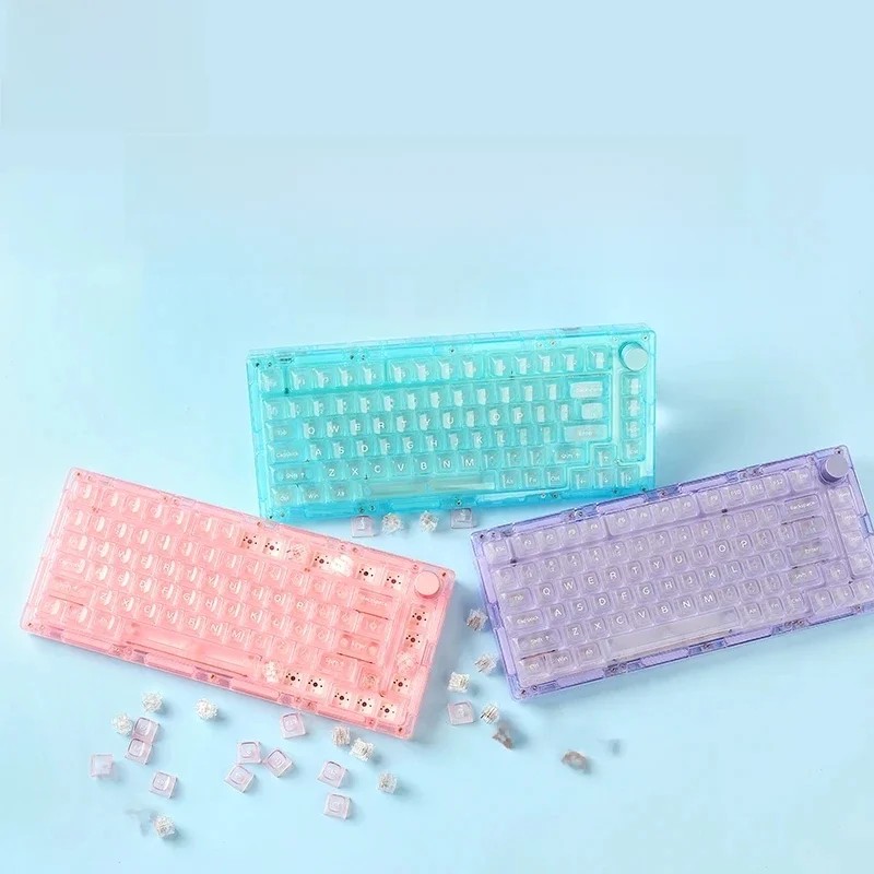 MonsGeek ICE 75 keyboard features a translucent design in pink, blue, and purple, showcasing a compact layout with visible key switches and a sleek, modern aesthetic.