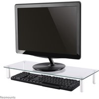Glass Neomounts NSMONITOR10 riser with metal legs, supporting a monitor, with space for a keyboard underneath.