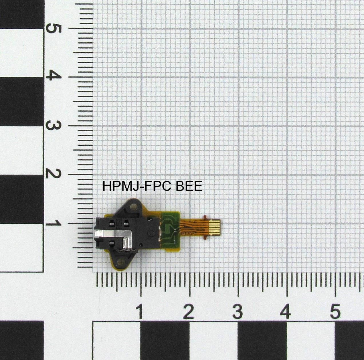 Small black and green electronic component with a connector, featuring a rectangular shape and metal contacts, placed on a grid background for scale.