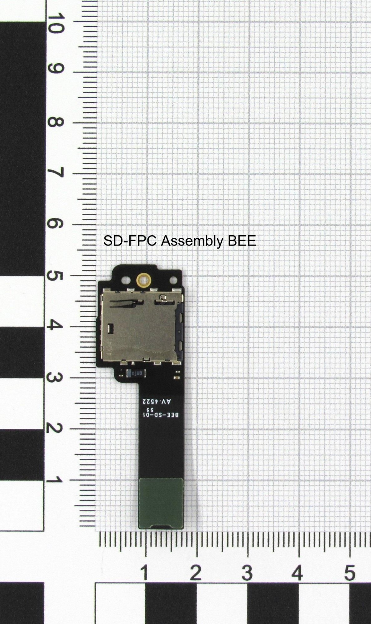 Nintendo SSY/FPC/SD/0X EE-S features a small black circuit board with a green connector, a gold contact area, and a slot for an SD card, displayed on a grid background.