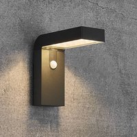 Black Nordlux Alya LED solar wall light with motion sensor, sleek rectangular design, mounted on a grey wall.