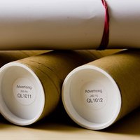 Brother DK11218 round labels, 24mm, white with black text, on brown cardboard rolls with white end caps.