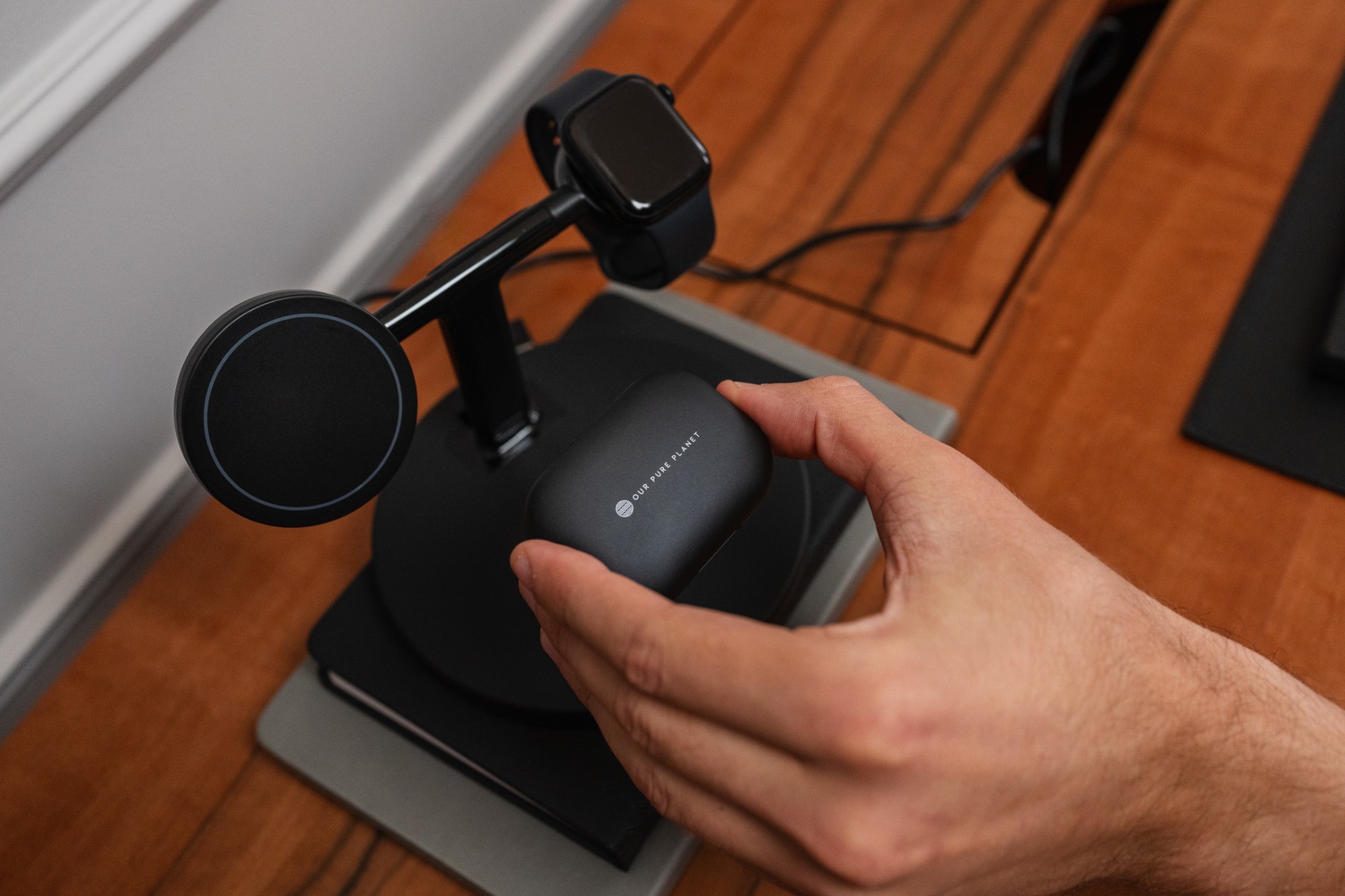 Black 3-in-1 wireless MagSafe charging dock with a sleek design, featuring a magnetic charging pad for iPhones, an Apple Watch holder, and a space for AirPods, set on a wooden surface.