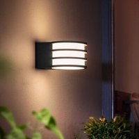 Black Philips Hue Lucca LED outdoor wall lamp with horizontal slats and warm white glow.