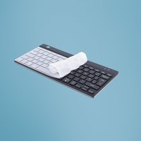 Clear R-Go Tools keyboard cover on black and white EU layout keyboard, rolled partially on keys.