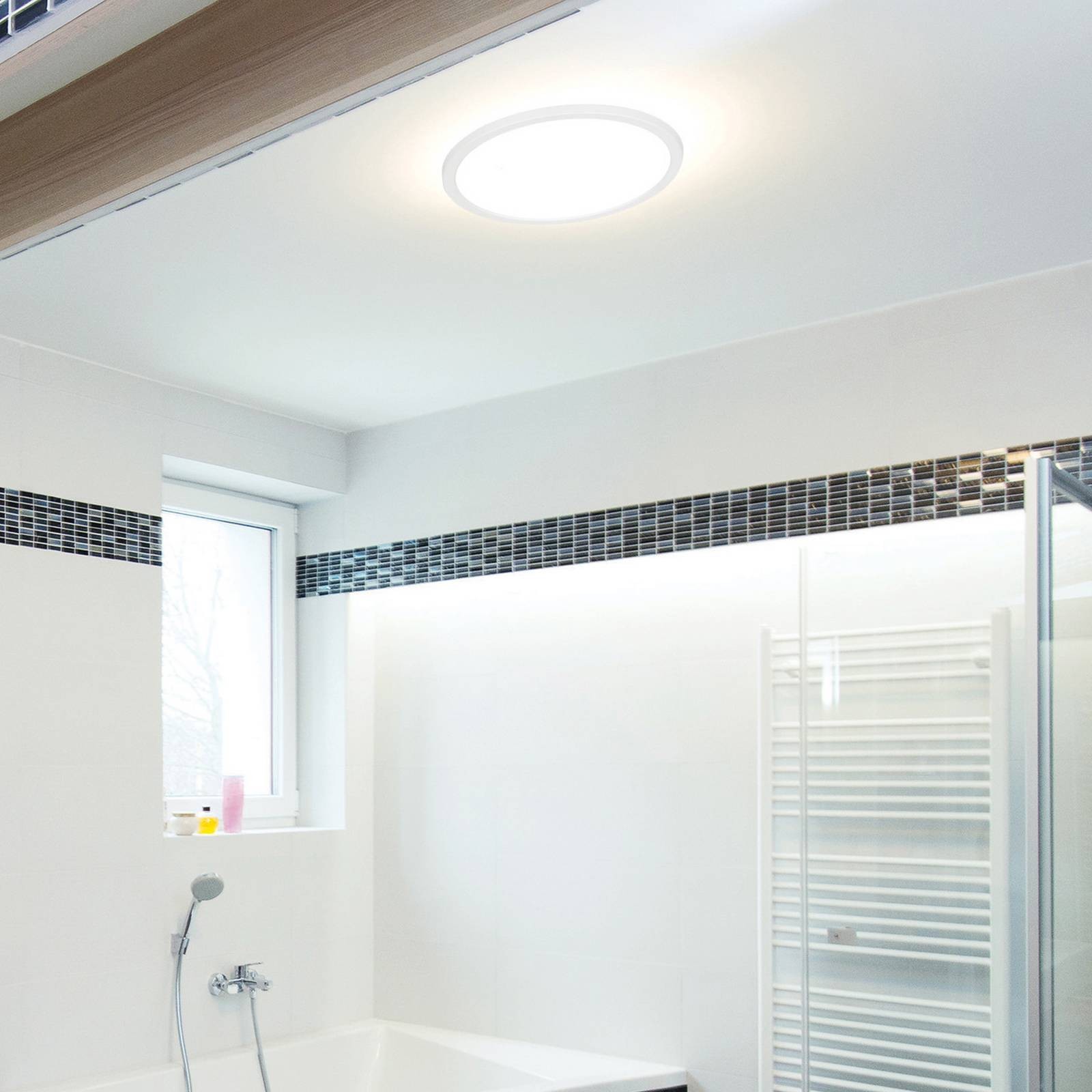 Sylvania 22W LED StepDim Round Ceiling Light in white, featuring a sleek design, emits warm 3000K light with 1950 lumens, installed in a modern bathroom setting.