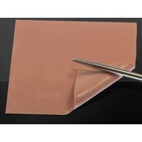 Thermal Grizzly Minus Pad 8, pink square thermal pad with corner lifted by metal tool.