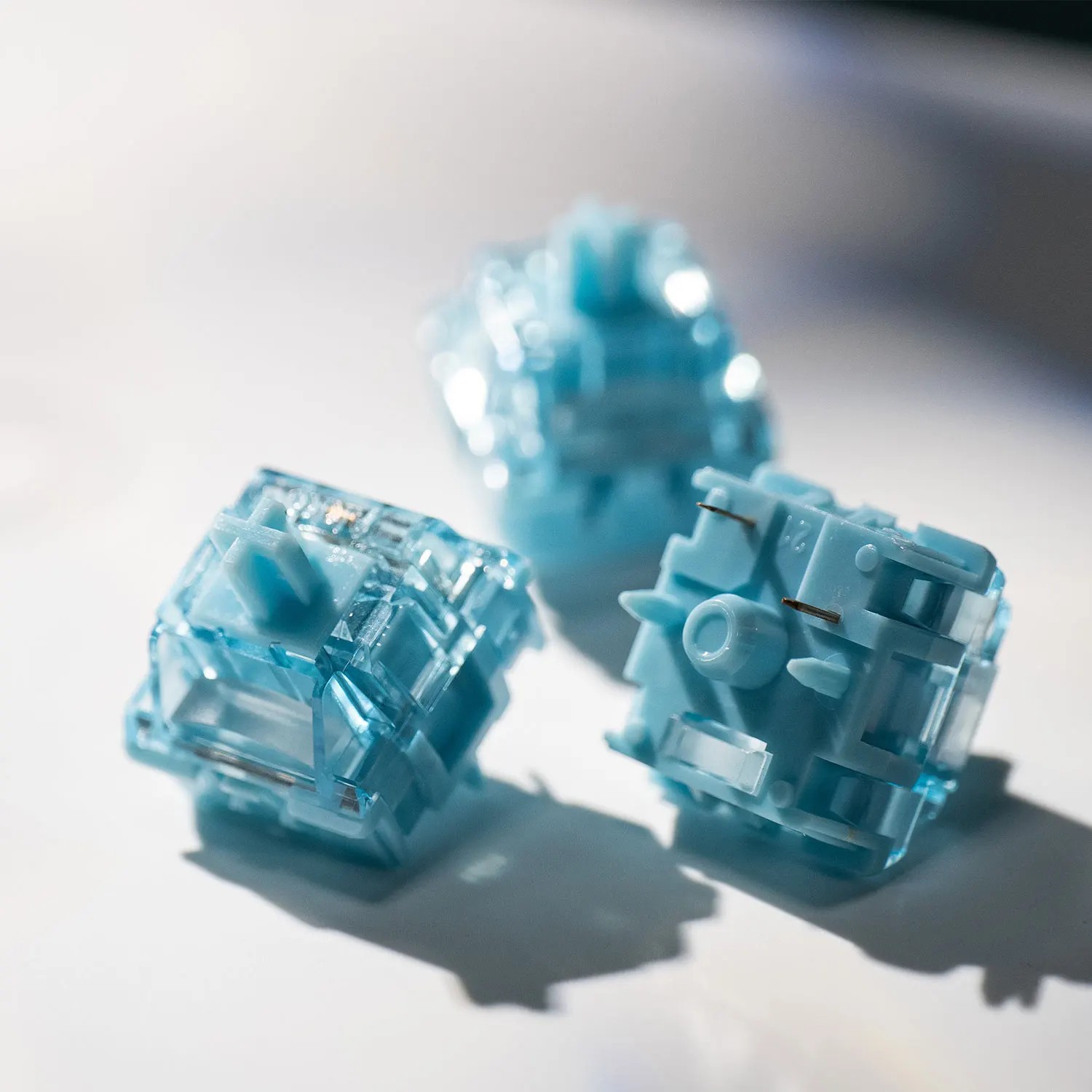 Three translucent creamy blue mechanical keyboard switches with a tactile design, featuring a 5-pin configuration and factory lubrication for smooth operation.