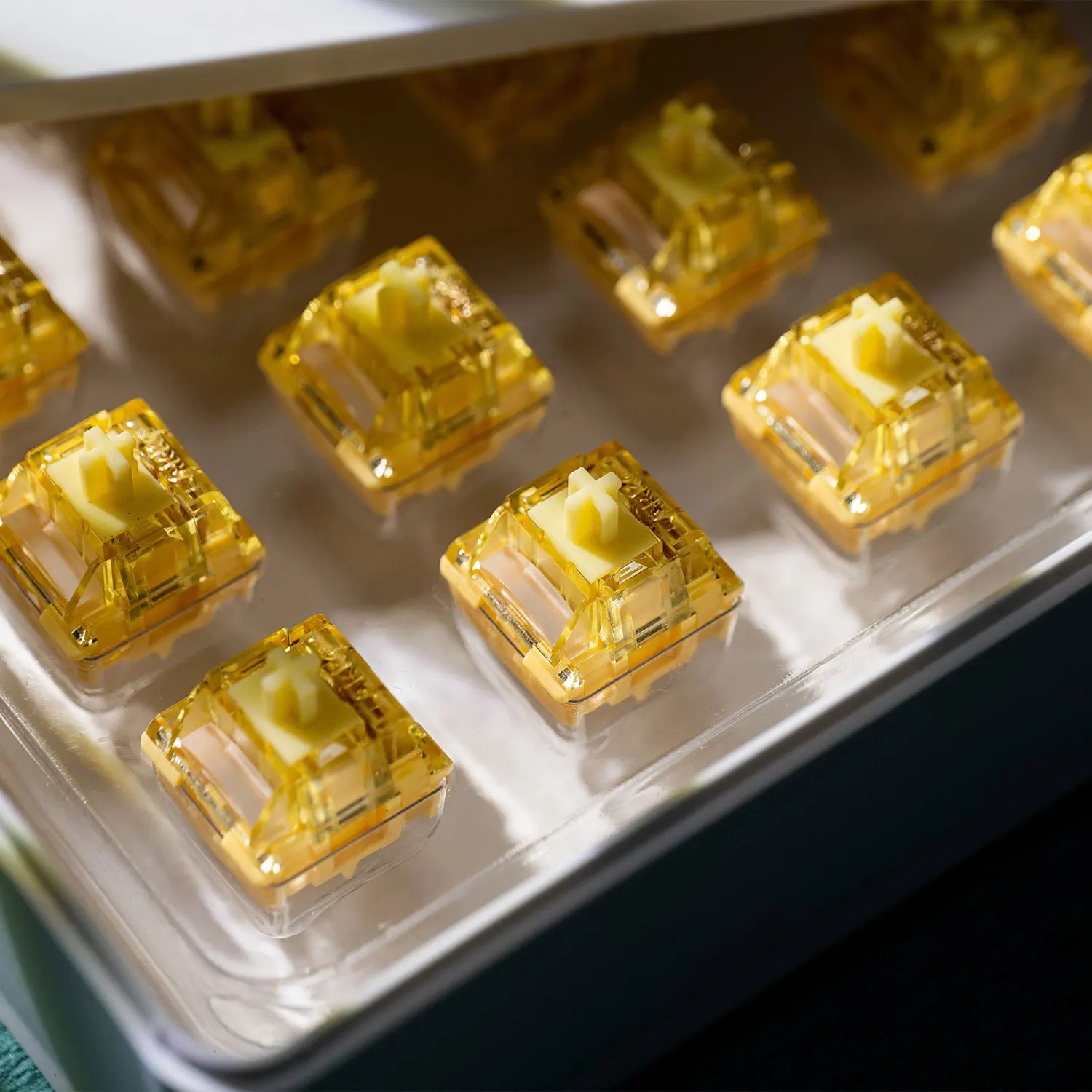 Cream yellow linear switches with a transparent housing, featuring a 5-pin design, arranged neatly in a tray, showcasing their factory-lubed finish for smooth operation.