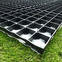Black plastic grid base kit for log cabin, 3x2m, with interlocking squares, placed on green grass.