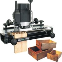 Black and silver Trend CDJ300 dovetail jig with adjustable knobs, wooden sample, and two open wooden boxes.