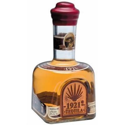 Clear glass bottle with a square base, featuring a gold and brown label, a red cap, and amber-colored tequila inside, labeled "1921 Añejo Tequila, 75 Cl."
