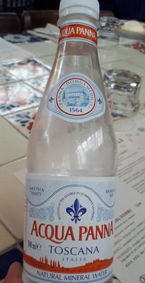 Clear glass bottle of Acqua Panna still mineral water, featuring a blue and red label with "TOSCANA" and "NATURAL MINERAL WATER" text, showcasing a sleek, elegant design.