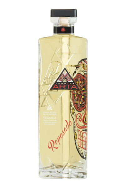 Clear glass bottle of Arta Reposado Tequila, 75 cl, featuring a colorful skull design and a black cap, with a golden liquid visible inside.