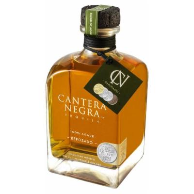 Clear glass bottle with a square shape, featuring a cork stopper, filled with amber-colored Cantera Negra Reposado Tequila, labeled with gold and green accents.