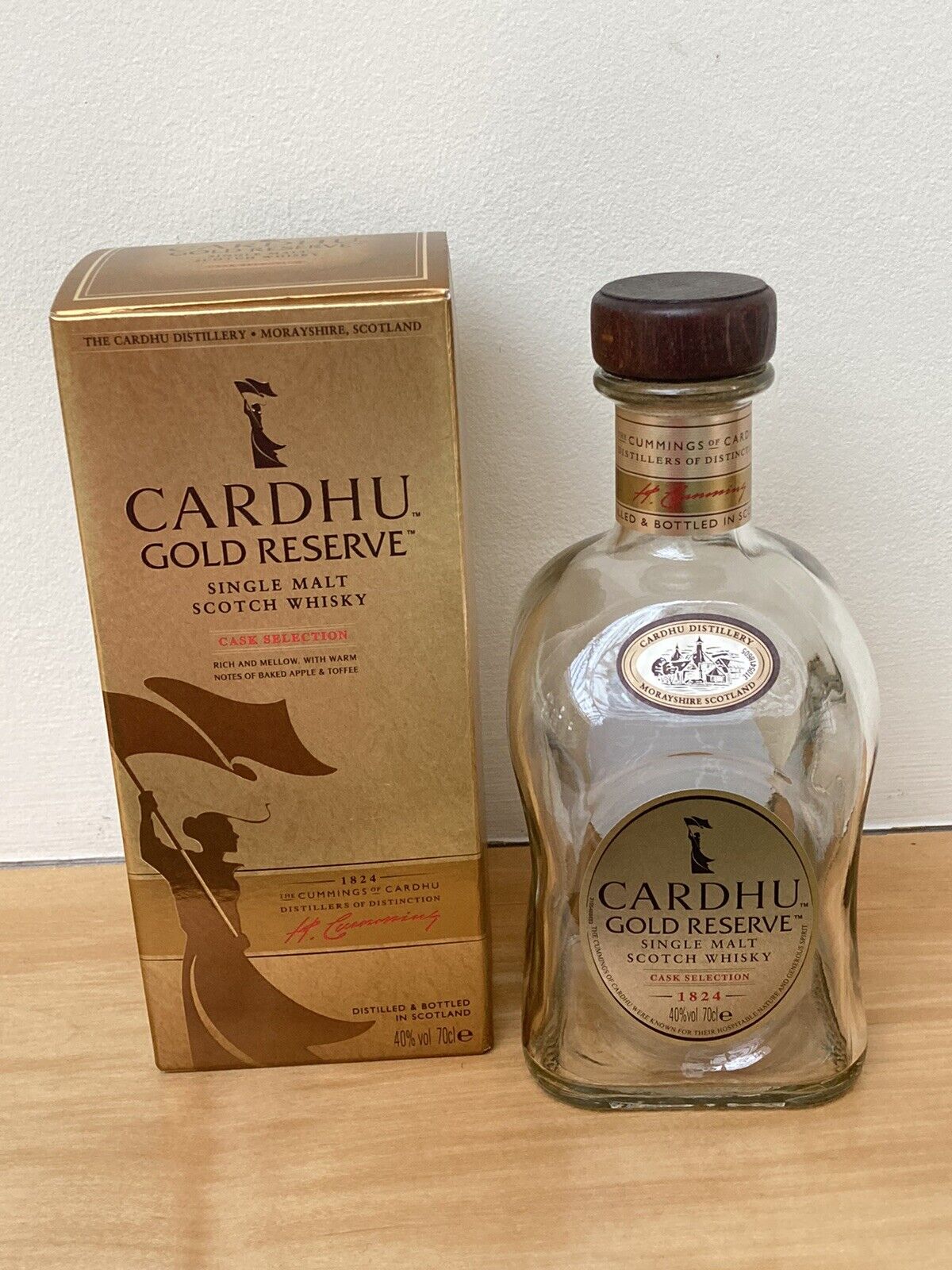 Cardhu 12 Year Old Single Malt Whisky in a clear glass bottle with a curved shape, featuring a gold label and a matching gold box with elegant design elements.