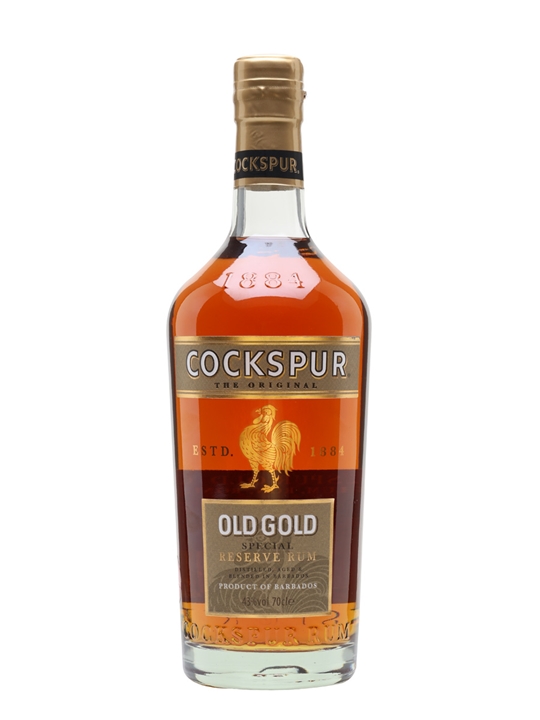 Clear glass bottle with a curved shape, filled with amber-colored rum, featuring a gold and black label with a rooster logo and the text "Cockspur Old Gold Special Reserve Rum."