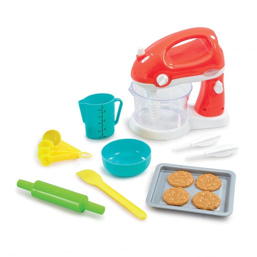 Brightly colored baking set featuring a red mixer, teal measuring cup, green rolling pin, yellow spatula, and a tray with four cookie-shaped pieces.