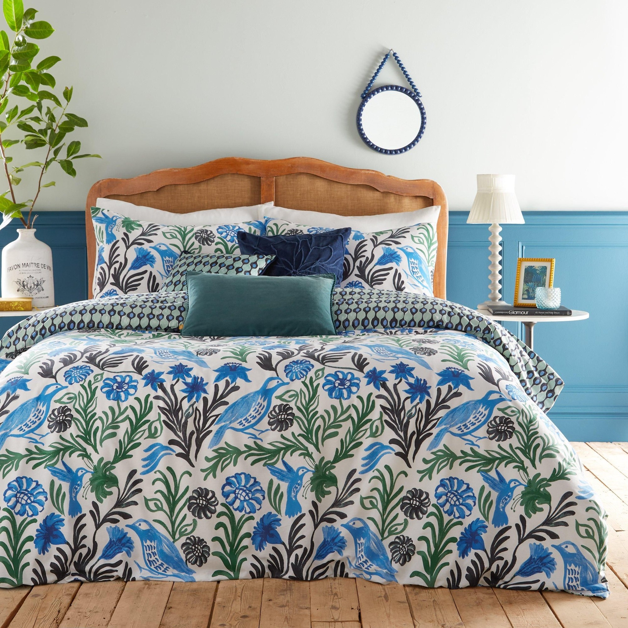 King duvet cover set featuring vibrant ocean blue and green floral patterns with birds, complemented by matching pillowcases and a textured teal accent pillow.