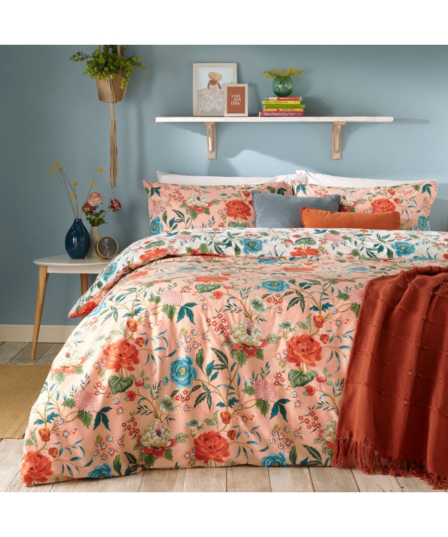 Reversible king duvet cover set featuring a pink floral design with red and blue flowers, complemented by matching pillow shams and a textured rust-colored throw.