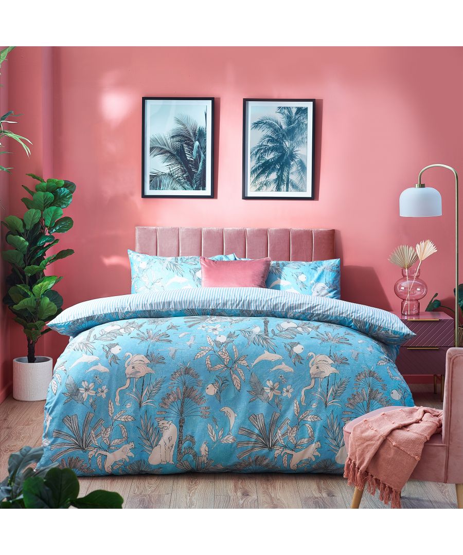 Reversible king duvet cover set in blue featuring botanical prints with palm leaves and flamingos, complemented by striped pillowcases and a pink headboard in a vibrant room setting.
