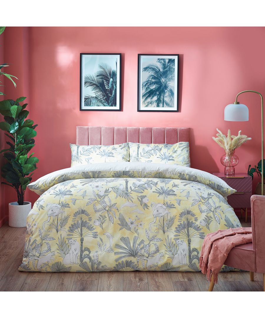 Tropical reversible duvet cover set featuring a yellow cotton fabric with palm leaf and floral patterns, sized for a super king bed, styled in a vibrant room with pink walls.