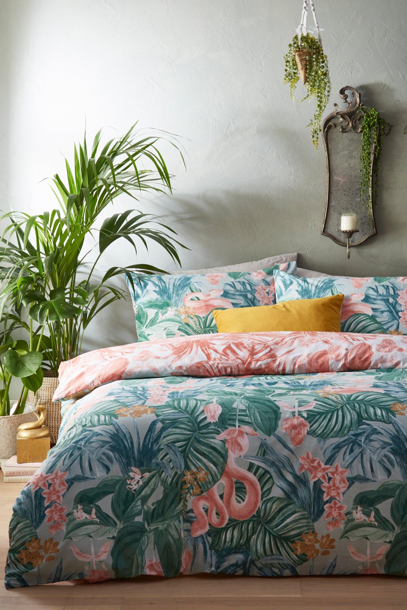 Tropical reversible duvet cover set featuring vibrant green and pink botanical prints, made of soft cotton, designed for a super king bed, complemented by a mustard yellow cushion.