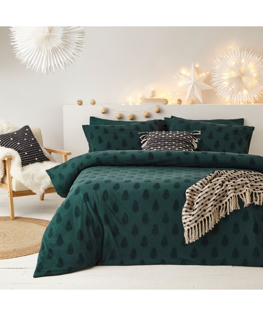 Tufted Tree Festive duvet cover set in deep green cotton, featuring a pattern of black trees, paired with matching pillowcases and a cozy throw blanket, set against a softly lit backdrop.