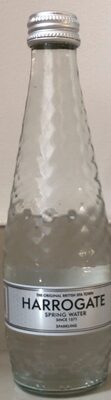 Clear glass bottle of Harrogate Spring Sparkling Water, featuring a textured surface, silver cap, and a label with "HARROGATE SPRING WATER" in bold lettering.