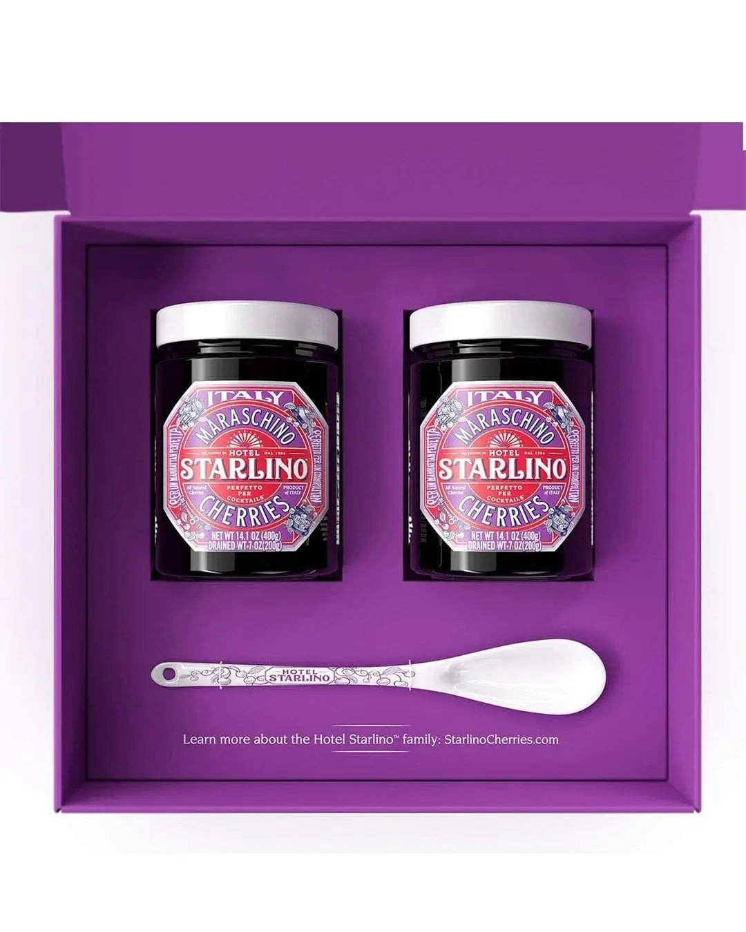 Two jars of Hotel Starlino Italian Maraschino Cherries (400 g each) in a purple gift box, accompanied by a white spoon, featuring vibrant labels with decorative designs.
