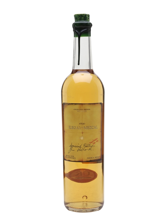 Clear glass bottle of Ilegal Anejo Mezcal, 70 Cl, featuring a cork stopper, a light amber liquid, and a decorative label with handwritten elements and a red stamp.