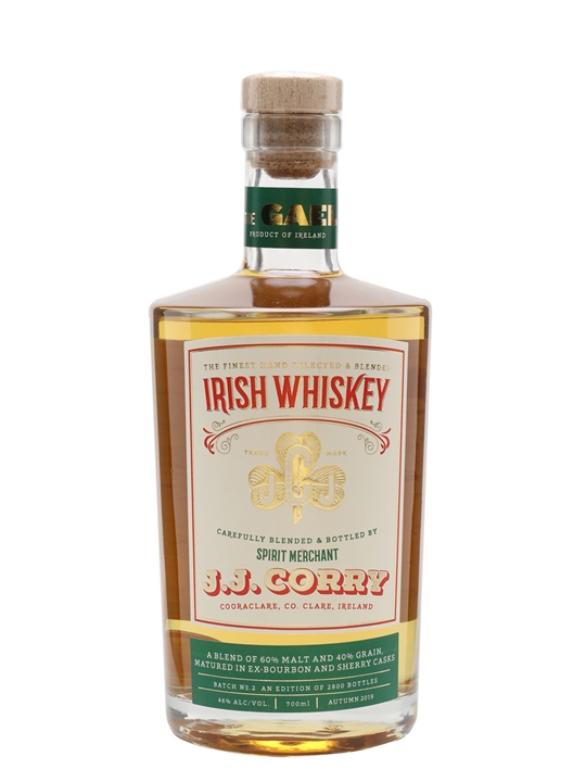 A clear glass bottle of JJ Corry, the Gael Whiskey, featuring a gold and white label with green accents, showcasing its Irish heritage and a cork stopper.
