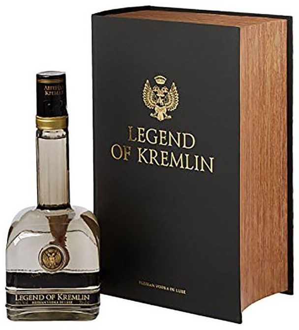 Clear glass bottle of "Legend of Kremlin Vodka" beside a black book-style box with gold lettering and an emblem, featuring a wooden spine and a smooth, elegant design.