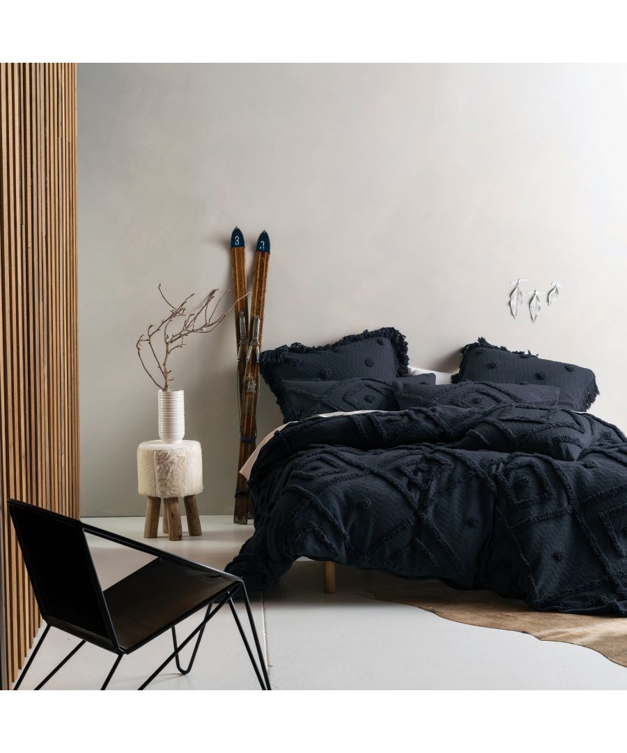 Dark blue linen duvet set with textured patterns, featuring a super king size, complemented by a minimalist chair and decorative elements in a stylish bedroom setting.