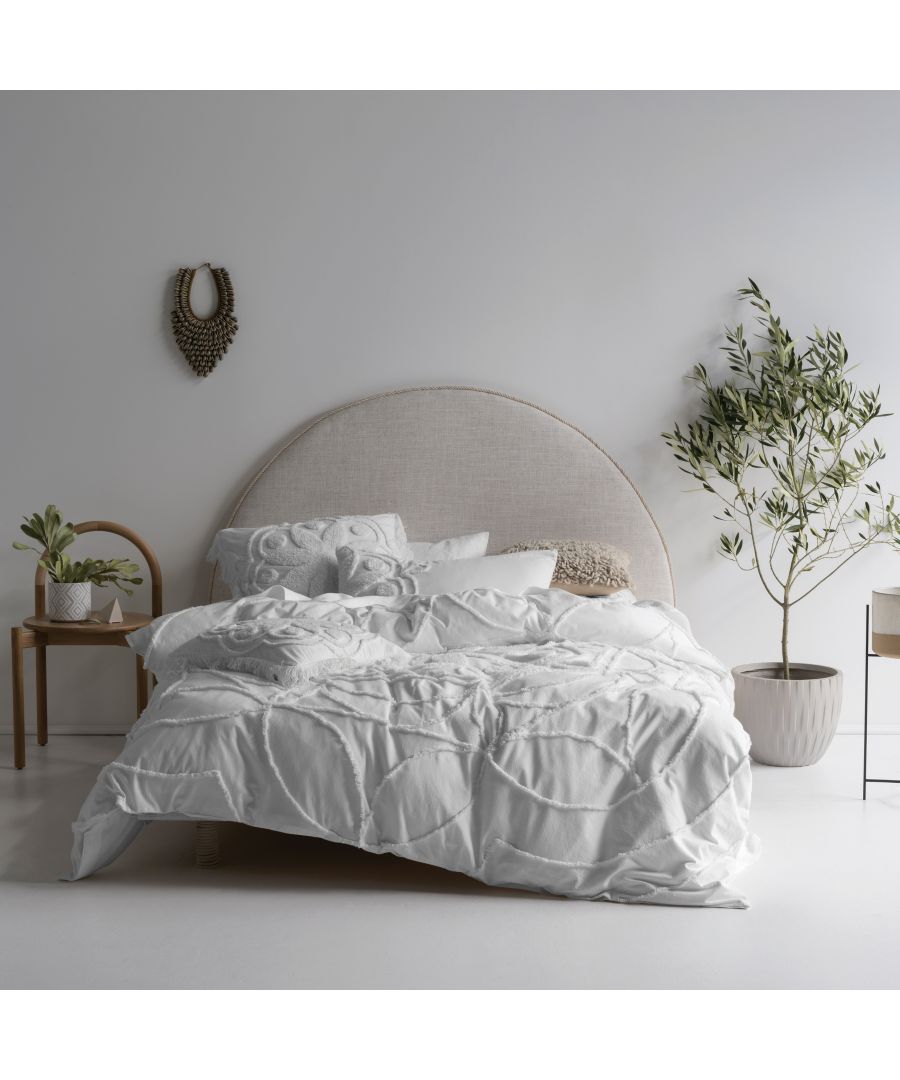 White linen duvet set featuring textured embroidery, styled on a king-sized bed with a neutral headboard, surrounded by minimalist decor and greenery.