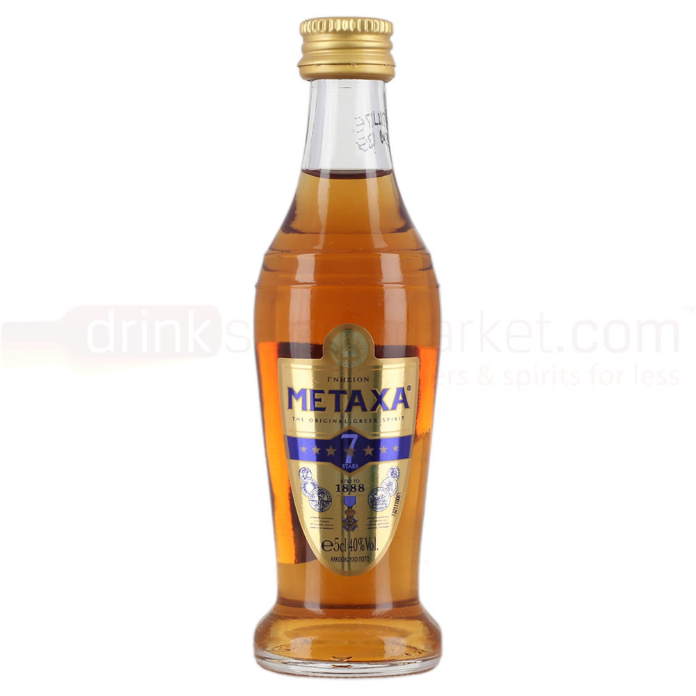 Clear glass bottle with a curved shape, filled with amber Metaxa 7 Star Brandy, featuring a gold cap and a blue and gold label with stars and a vintage design.