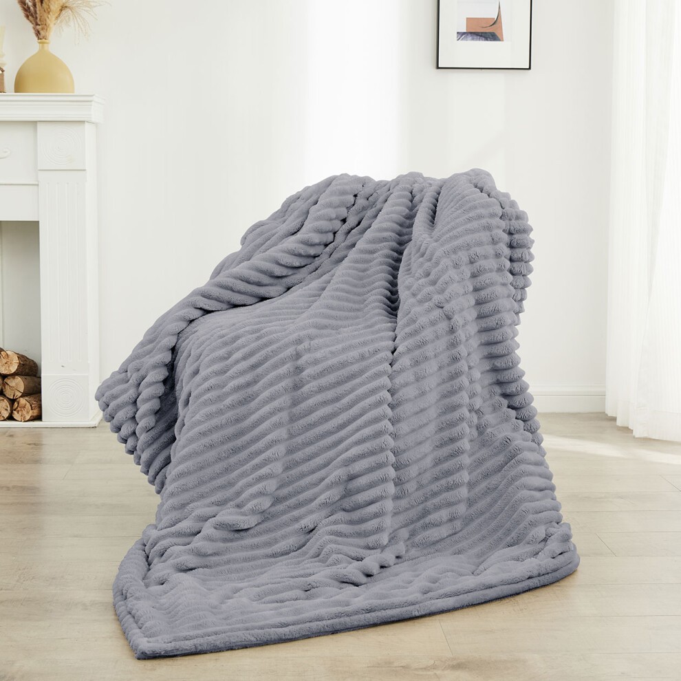Soft, grey electric heated blanket with a textured, ribbed design, ideal for caravans and motorhomes, draped casually on a light wooden floor.