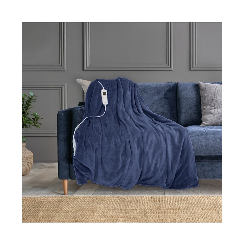 Reversible electric heated throw blanket in a deep navy blue, made of soft material, draped over a dark sofa with a control cord visible.