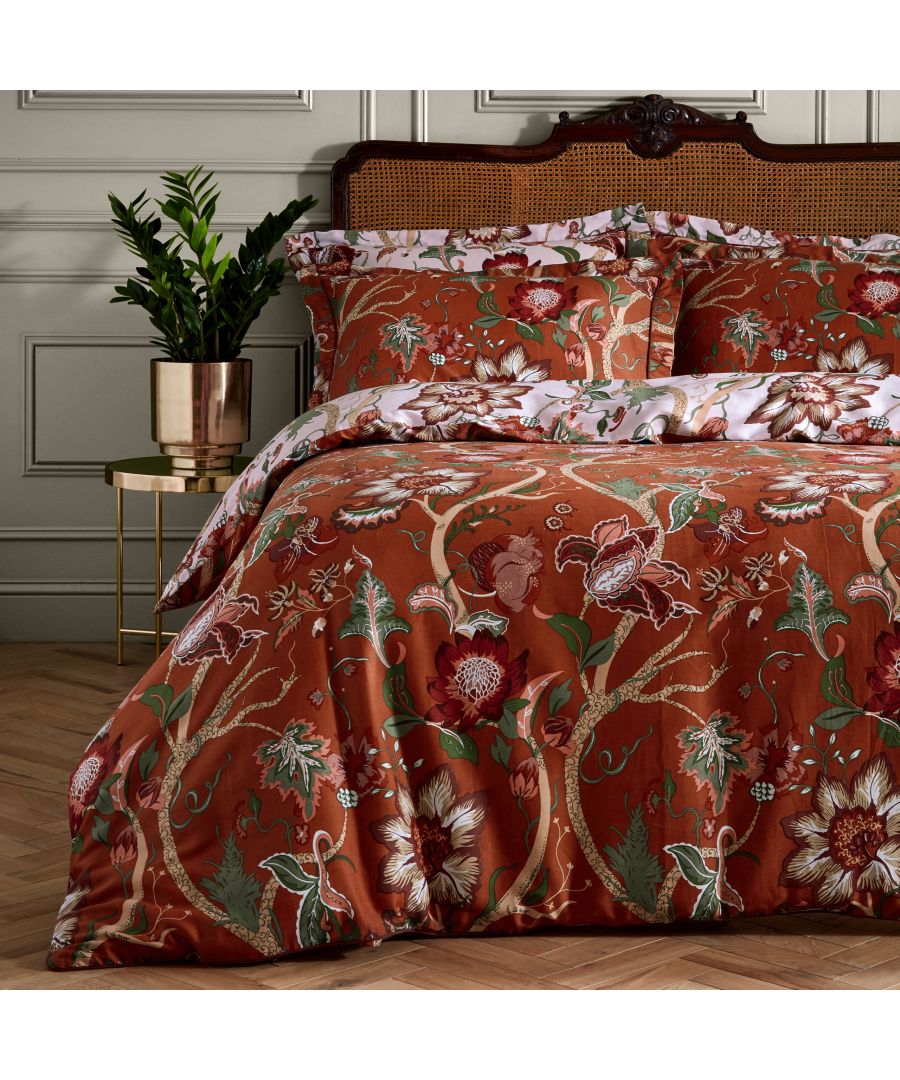 Rust cotton duvet cover set featuring vibrant floral patterns, complemented by matching pillowcases, set against a textured headboard and a decorative plant in a metallic pot.