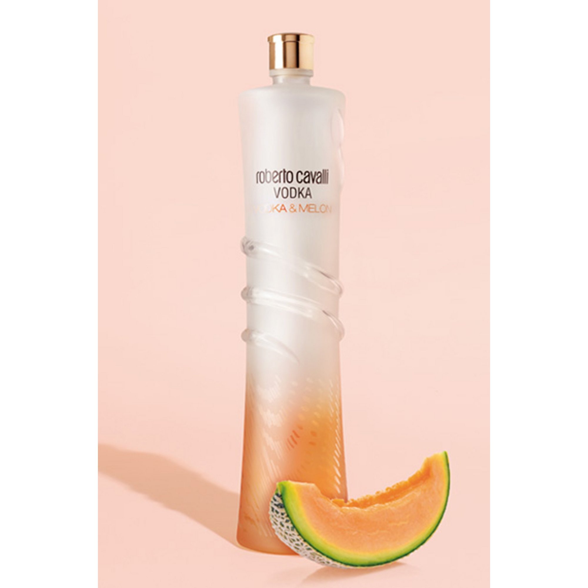 Clear, sleek bottle of Roberto Cavalli Vodka Melon with a gradient from white to light orange, featuring a gold cap and a slice of cantaloupe beside it.