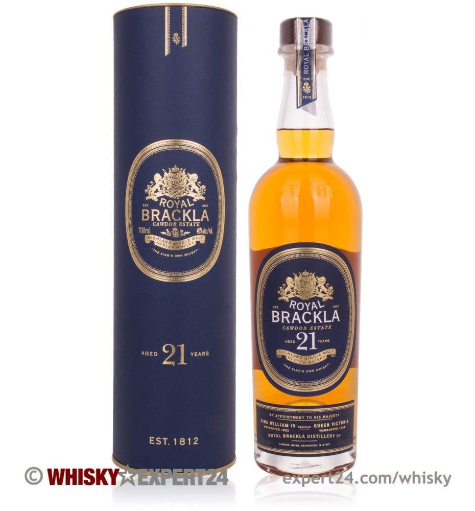 Royal Brackla 21 Year Old whisky in a clear glass bottle with a cork stopper, featuring a gold label and a blue cylindrical box with gold accents.