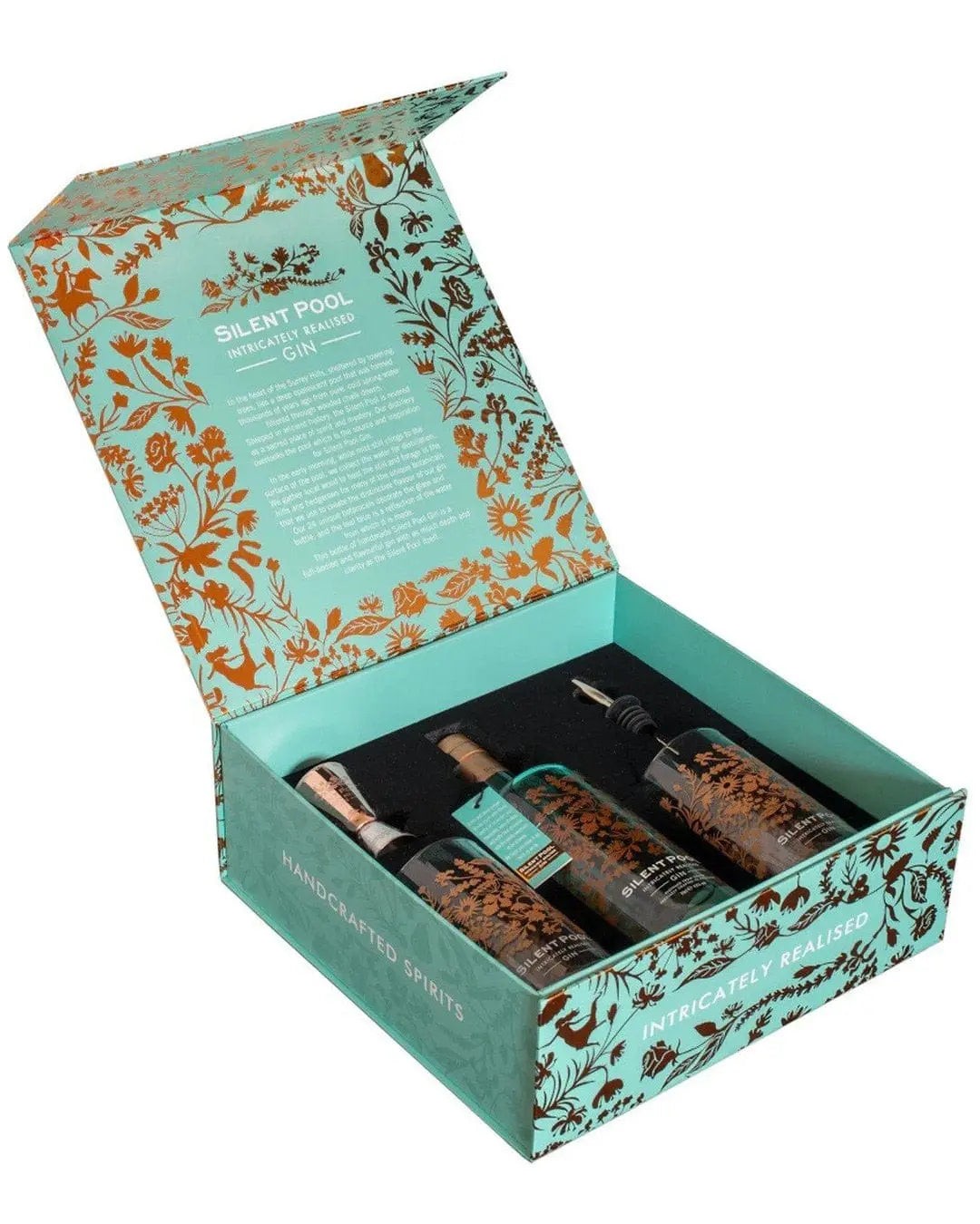 Luxury gift box featuring three bottles of Silent Pool gin, adorned with intricate floral designs in turquoise and gold, with a soft black interior for protection.