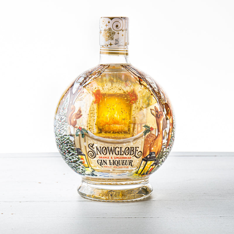 Round glass bottle of Snow Globe Orange & Gingerbread Gin Liqueur, featuring festive illustrations, a golden liquid, and a snow globe effect with a winter scene inside.