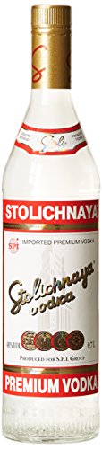 Clear glass bottle of Stoli Premium Vodka with a red and white label, featuring the word "Stolichnaya" in bold, and a gold emblem with five circles at the bottom.