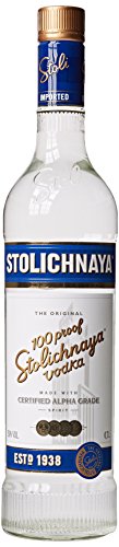 Clear glass bottle of Stolichnaya 100 Proof Vodka, 70 cl, featuring a white label with gold lettering, a gold cap, and a vintage design, established in 1938.