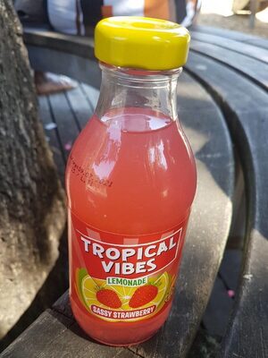 Bright pink lemonade in a clear bottle with a yellow cap, featuring a label that reads "TROPICAL VIBES" and "SASSY STRAWBERRY," set against a wooden background.